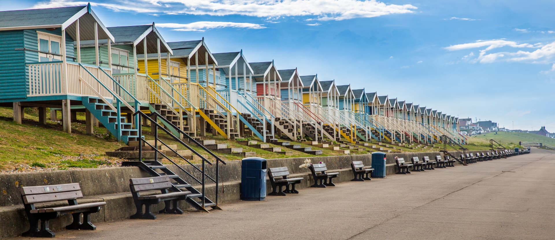 Colourful seaside beach huts along a sunny promenade
